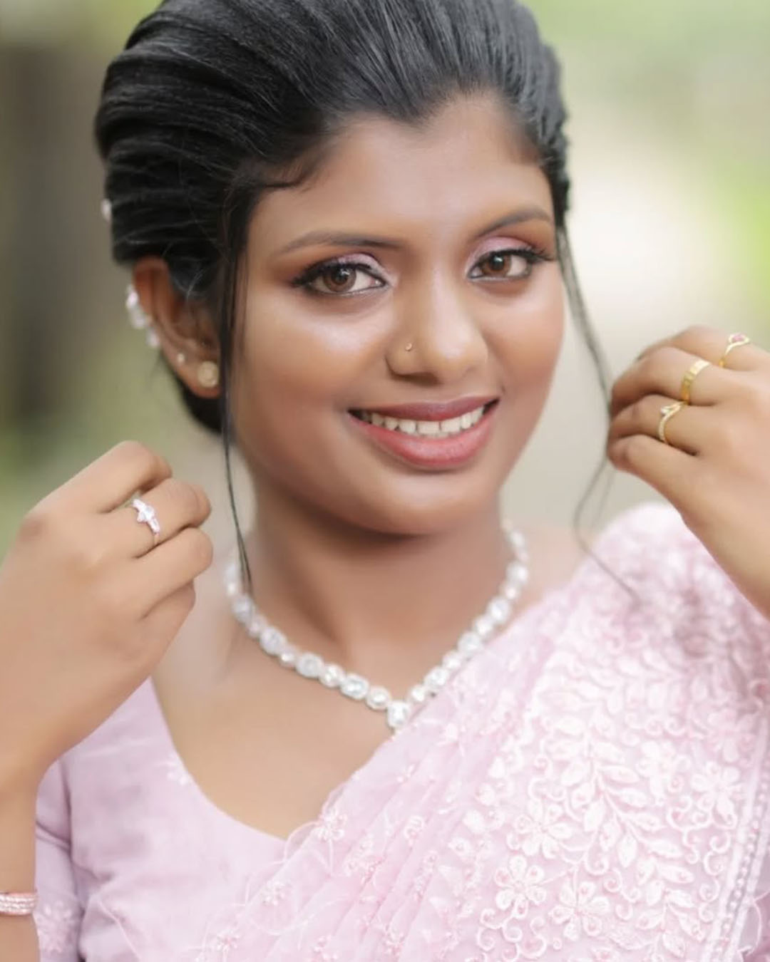 Portrait of woman in light pink outfit wearing pearl necklace and ring
