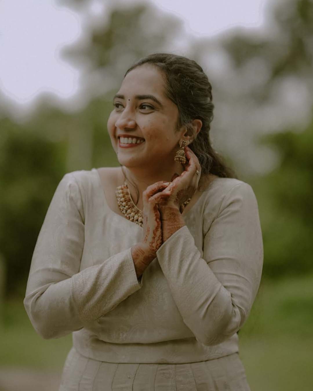 Woman in white dress with natural makeup smiling outdoors